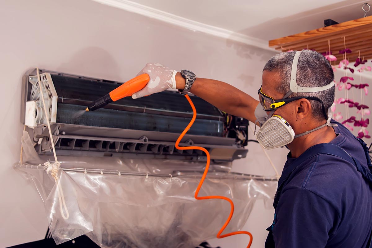 Man worker doing professional cleaning of air conditioning.